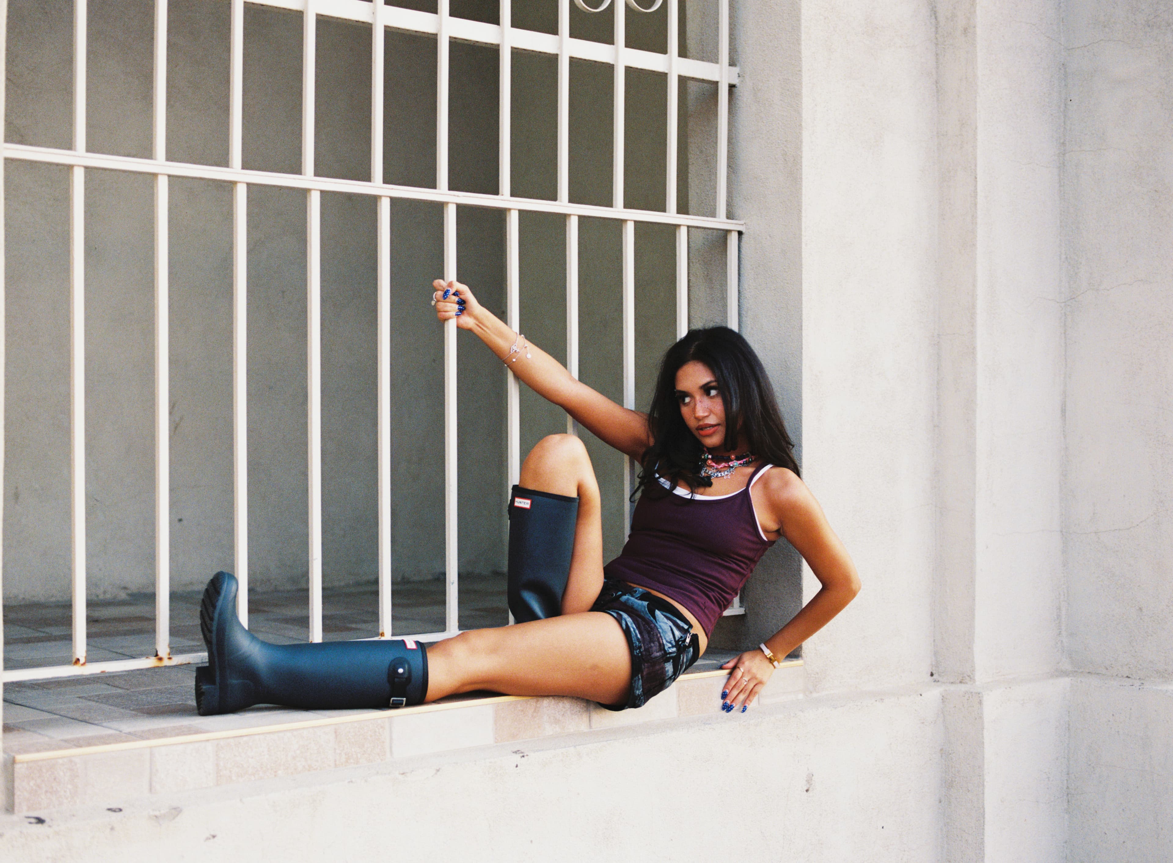 Woman reclining on a ledge in front of white window bars.