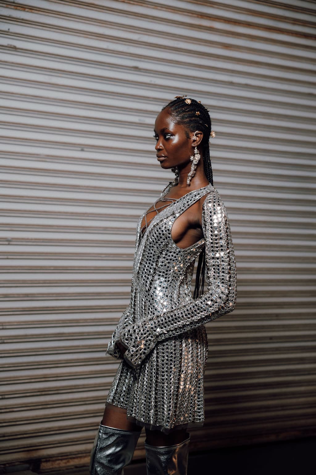Profile portrait of a model in a mirrored silver mini dress.