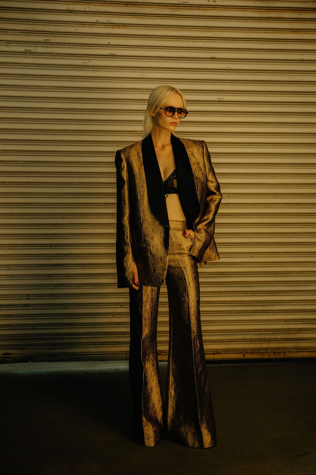 Model in a bronze suit photographed under warm backstage light.