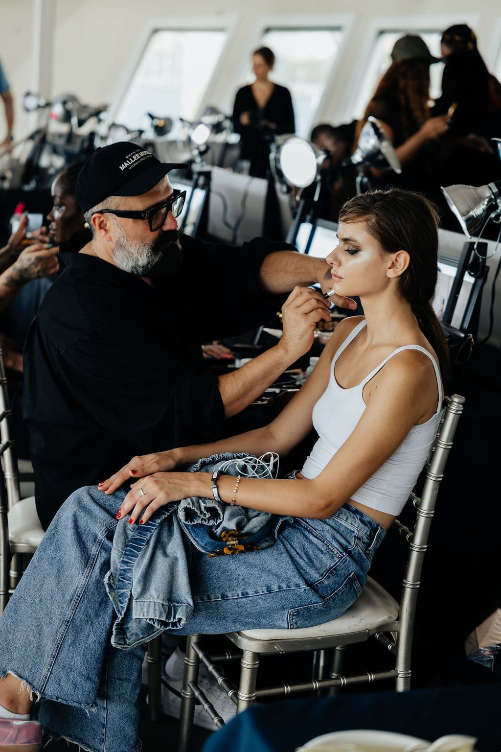 A makeup artist preparing a model backstage before the show.