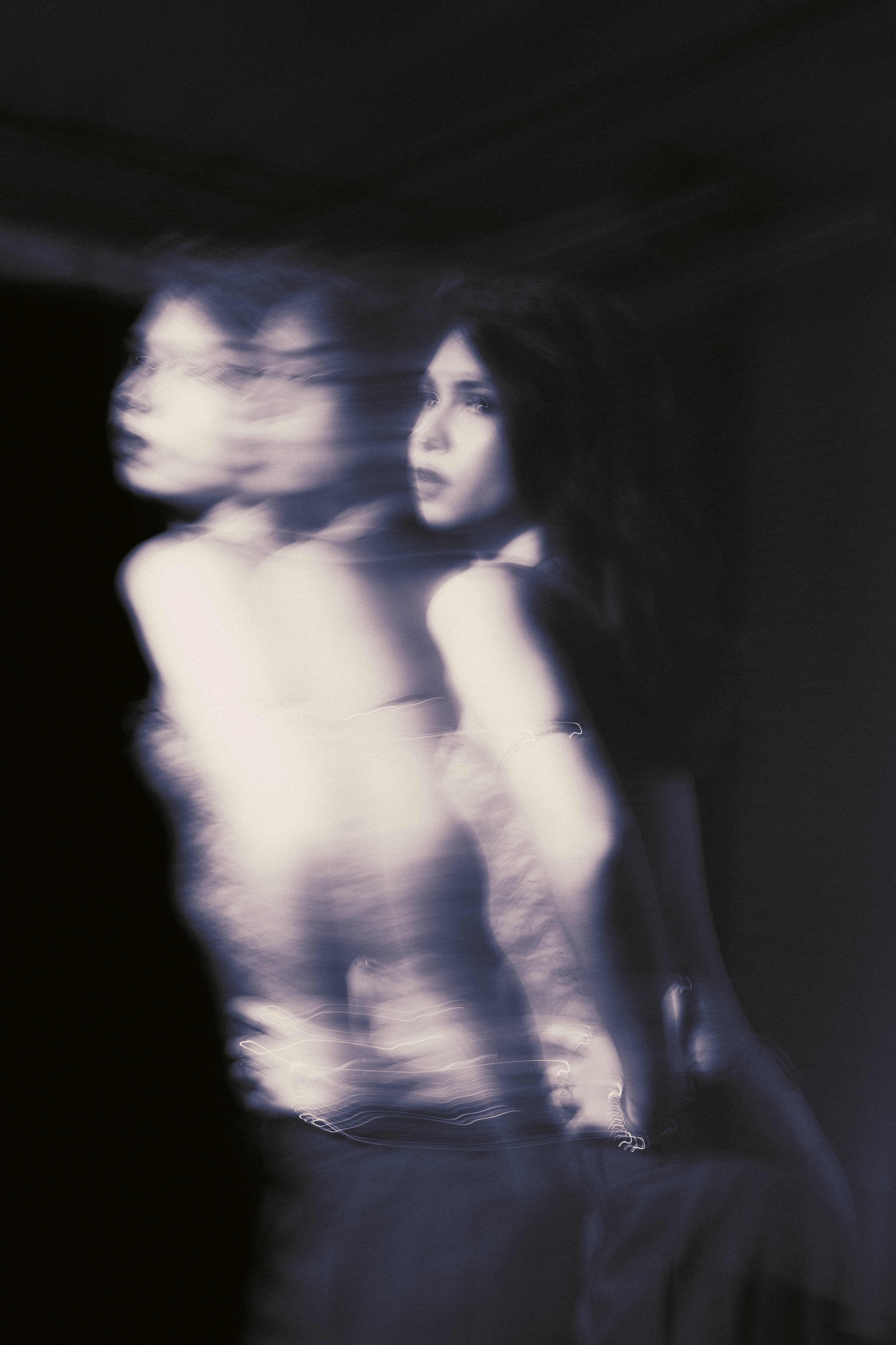 Multiple-exposure motion portrait of a woman in cool blue light.