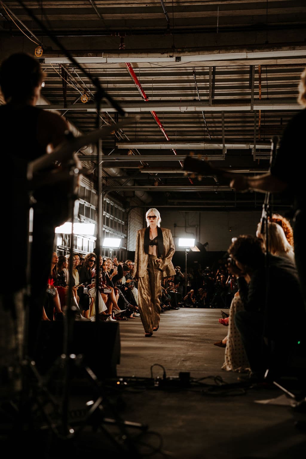 A model walking the Cucculelli Shaheen SS26 runway between the live band and audience.