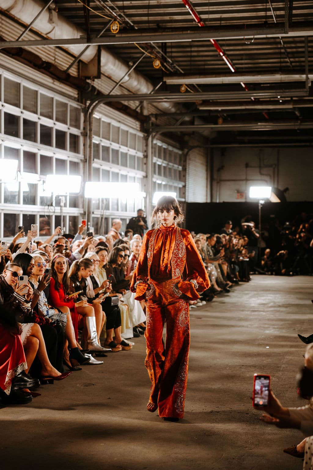 A model in an orange Cucculelli Shaheen look walking the runway.