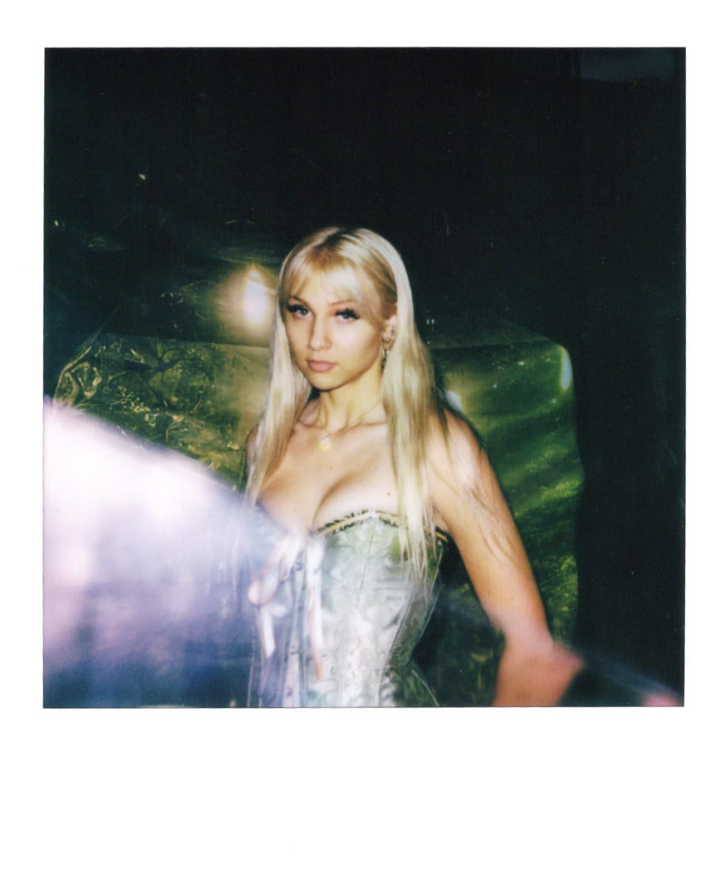 Polaroid of a woman in a silver corset caught in a flash flare.