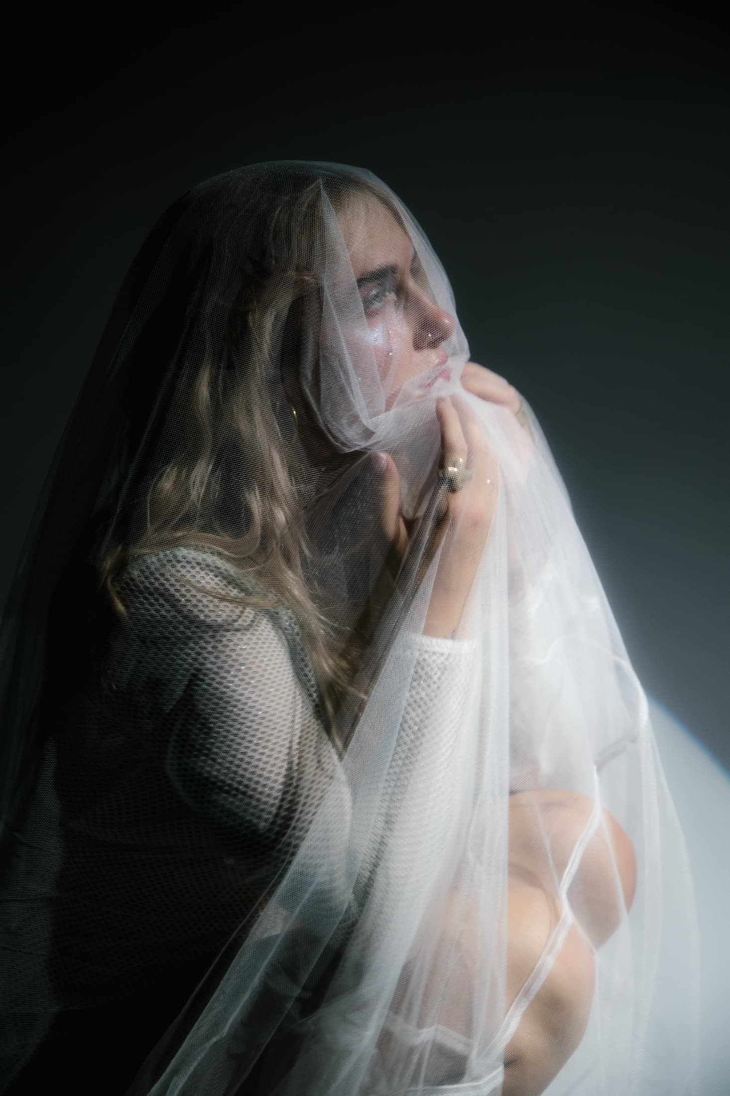 A seated subject photographed through a translucent veil.