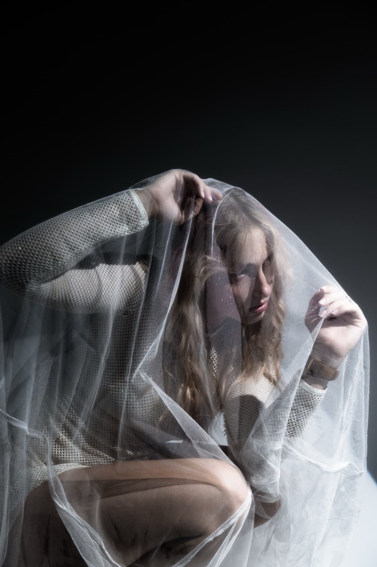 An editorial portrait viewed through a translucent textile.