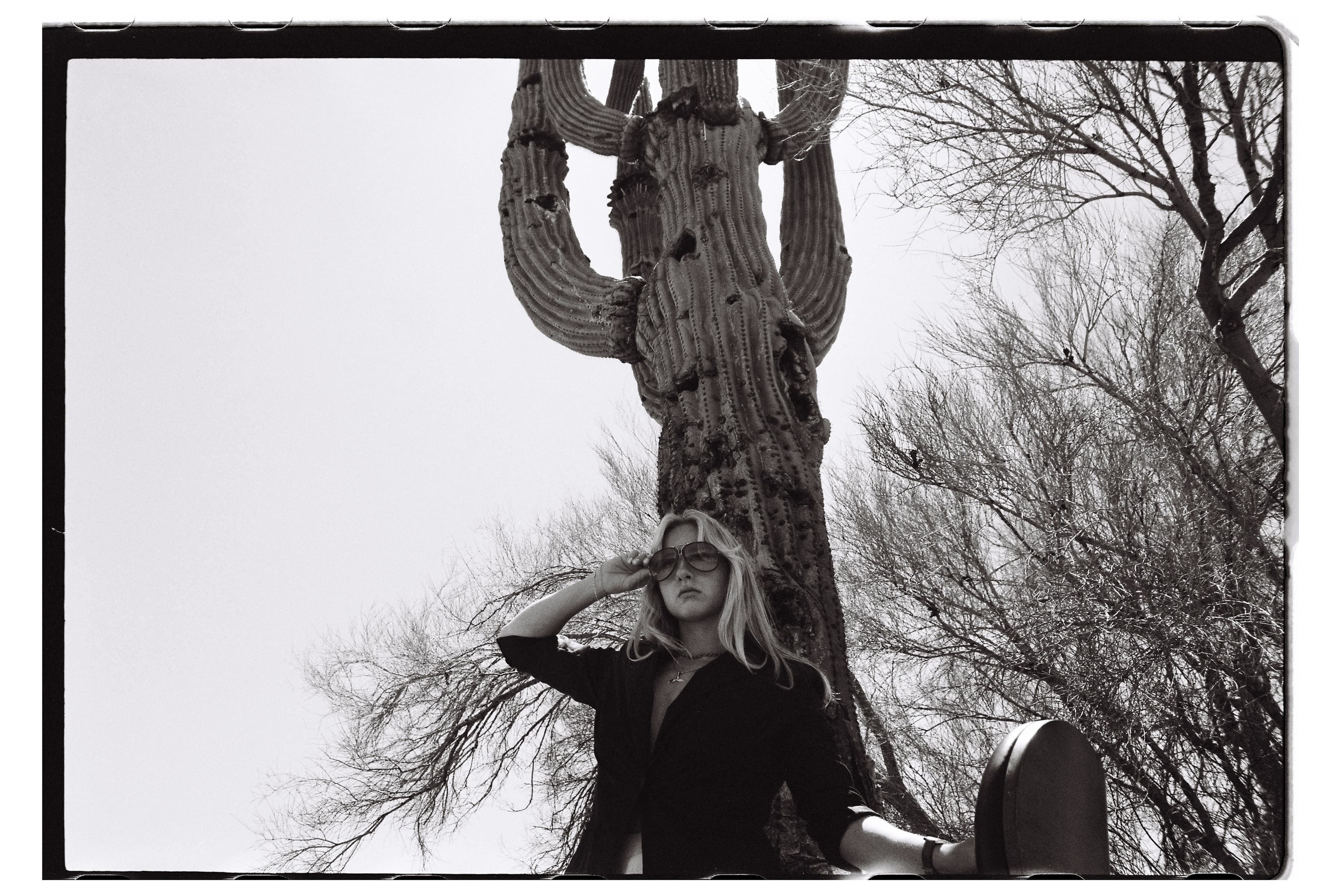 Black-and-white self-portrait of Hannah Warren beneath a saguaro cactus.