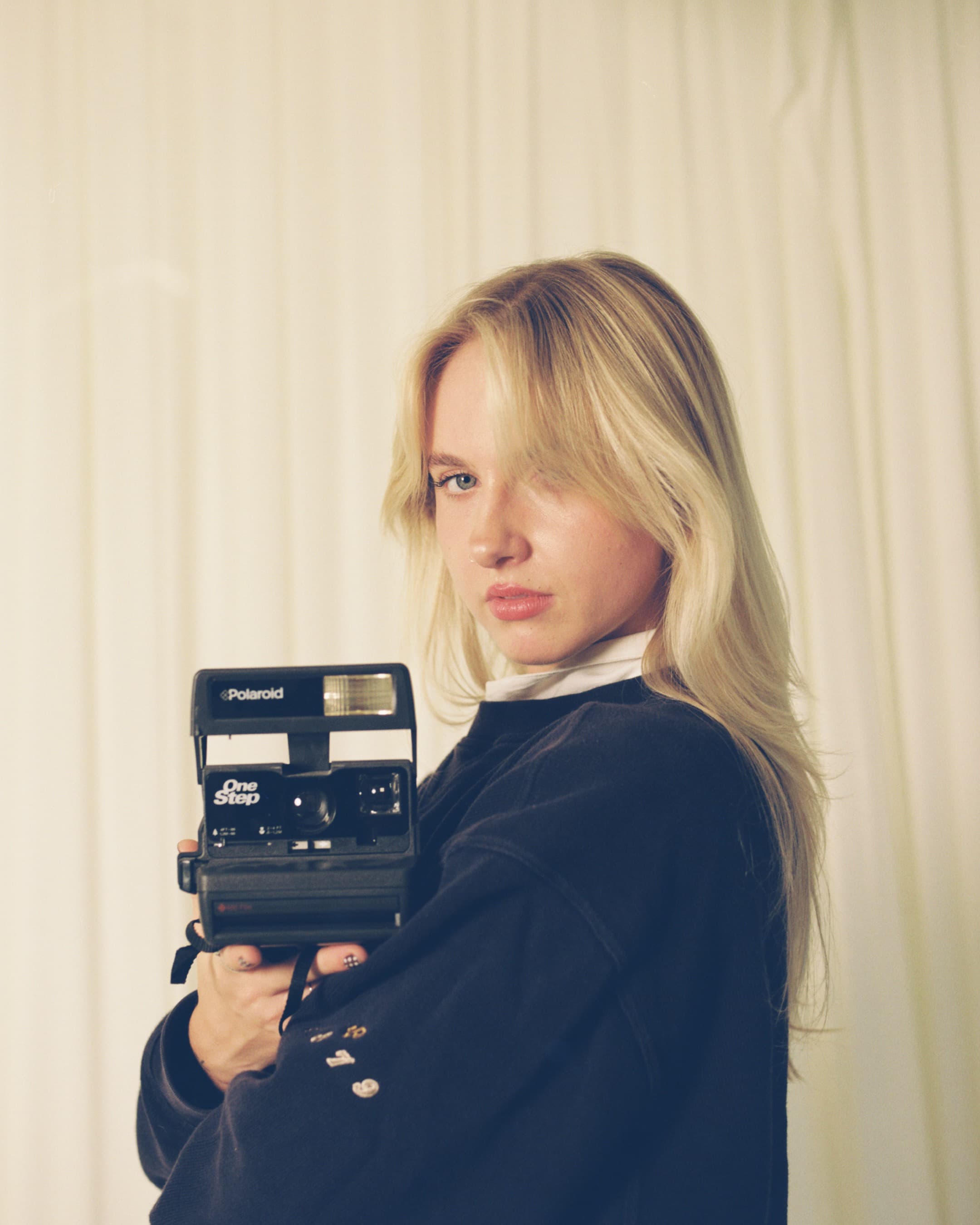 Self-portrait of Hannah Warren holding a Polaroid camera.